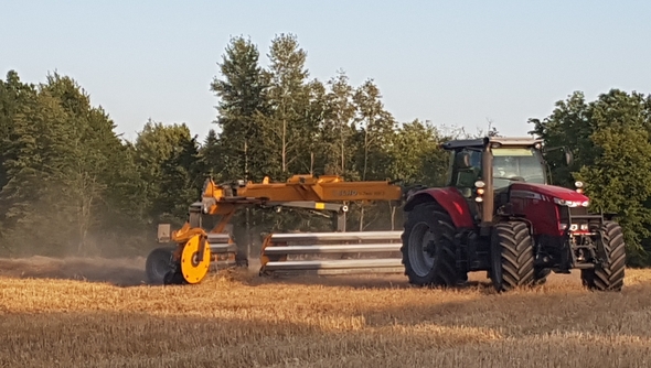 Traktor på åker med skördad spannmål.