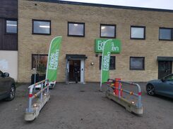 Fotografi av kontorsbyggnad med gröna flaggor utanför.