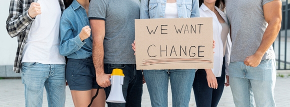 Fem ungdomar står och håller upp en skylt med texten "we want change"