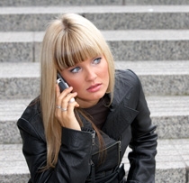 Ung sminkad kvinna talar i telefon och ser orolig ut.