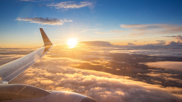 Flygplansvinge i motljus uppe bland molnen