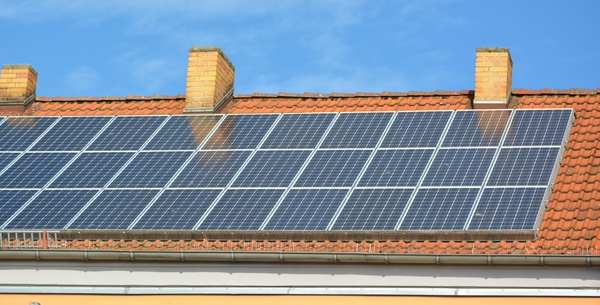 Solpaneler monterade på ett tegeltak under en klarblå himmel.