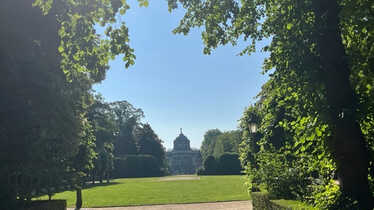 Foto på en park med ett vitt slott i bakgrunden.
