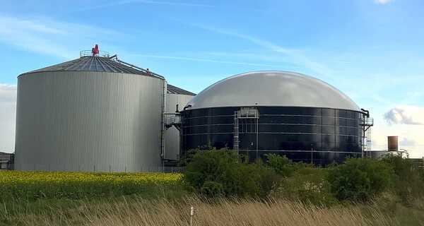 Biogasanläggning och silo på en solig dag med molnig himmel. Biogasanläggning och silo på en solig dag med molnig himmel.
