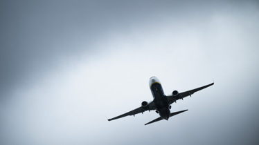 Flygplan sedd underifrån mot molnig himmel