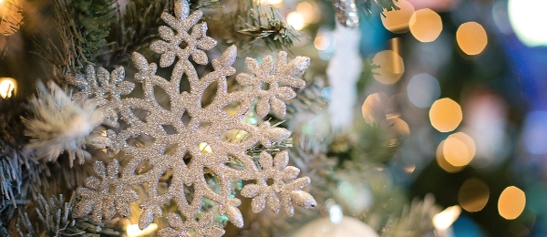 Glittrande snöflinga dekoration i en julgran med suddig bakgrund av varma ljus.