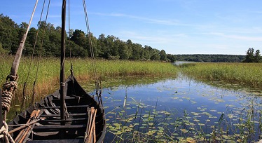 En gammal träbåt som ligger i vatten med näckrosor