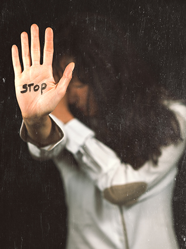 Närbild på en kvinnas utsträckta handflata med ordet STOP skrivet i tusch 