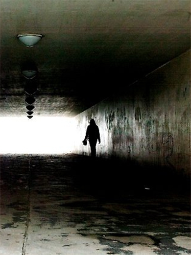 Silhuetten av en människa syns i en mörk vägtunnel