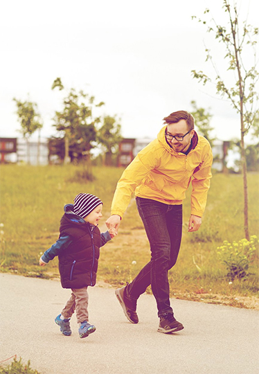 En skrattande pappa springer hand i hand med sitt skrattande lilla barn