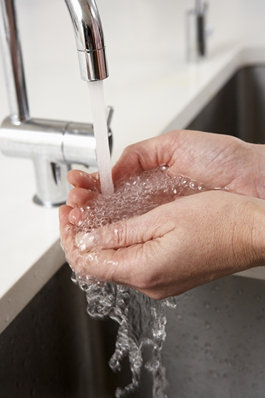 Närbild på händer som tvättas under kran med rinnande vatten