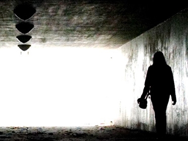 Svartvit bild på en person som går i en tunnel i motljus 