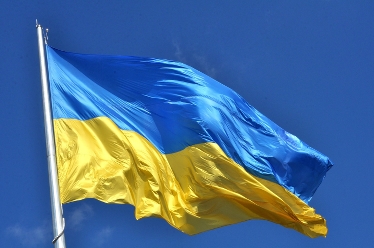 Ukrainas blågula flagga vajar i vinden mot en blå himmel