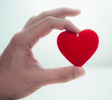 En hand som håller i ett rött hjärta.
