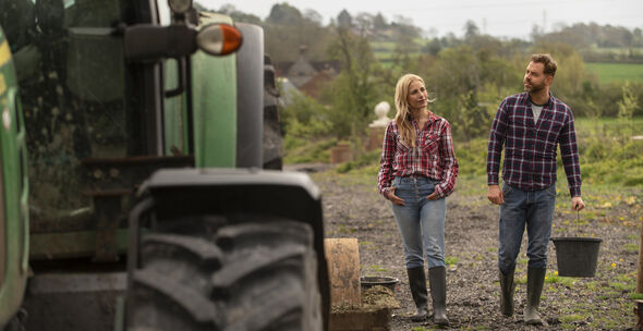 Kvinna och man går bredvid en grön traktor