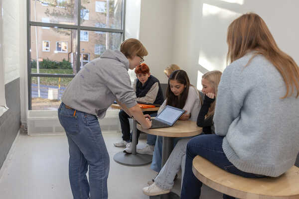 Elever sitter i skolkorridoren och pratar