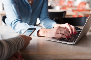 Händer med laptop och telefon