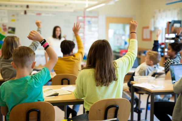 Elever i klassrummet räcker upp händer