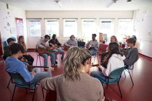 Elever och lärare spelar gitarr på musiklektion