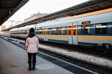 Person som väntar på tåget vid en järnvägsstation.