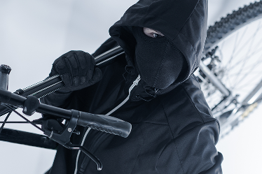 Svartklädd maskerad person bär på en cykel. Foto: Mostphotos.com