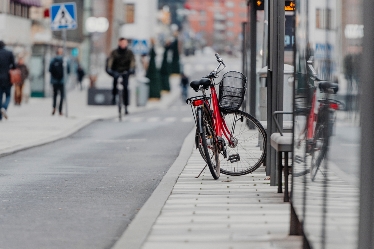 En parkerad cykel vid en trottoarkant på en stadsgata.