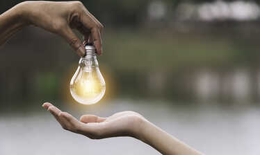 En hand som ger en annan hand en lysande glödlampa/idé. Foto: Krisana Antharith / Mostphotos.com
