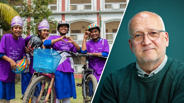 Grupp av leende skolflickor i lila tröjor med cykel och artikelförfattaren i grön tröja.