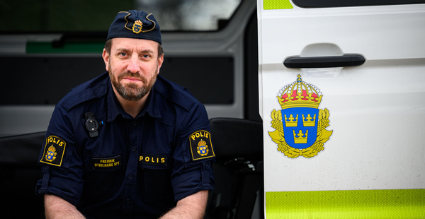 Svensk polisman framför en polisbil med riksvapnet.