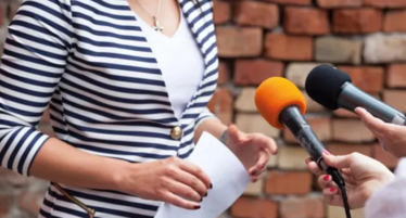 Mikrofoner som stäcks mot en kvinna.