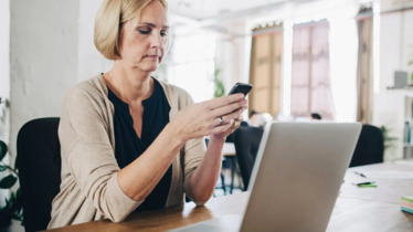 Kvinna som tittar på sin mobil som hon håller med båda händerna