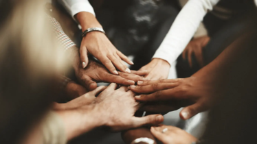 Händer som hålls mot varandra i mitten. 