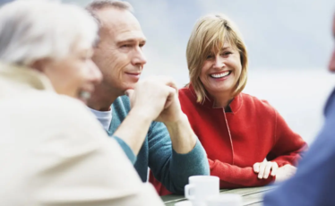 Personer som sitter vid ett bord utomhus och samtalar.