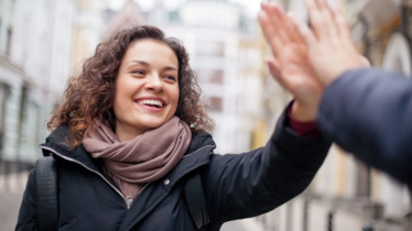 En tjej som gör high five med en hand som man ser baksidan av. 