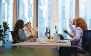 Personer runt ett bort som samtalar och arbetar.