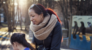 En kvinna i solsken som tittar ner mot annan kvinna. 