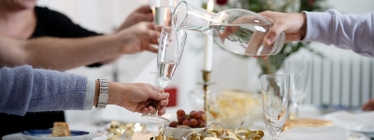 Hand håller fram champagneglas som fylls med kranvatten från en karaff