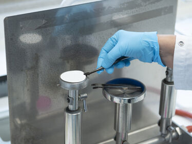 Hand i blå handske arbetar i laboratorium