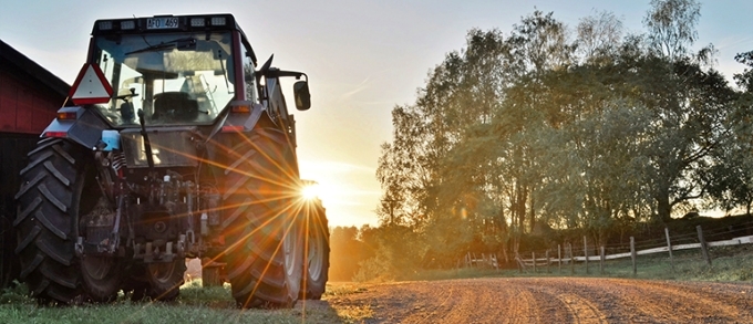 Traktor parkerad bredvid en grusväg i solnedgången på landsbygden.
