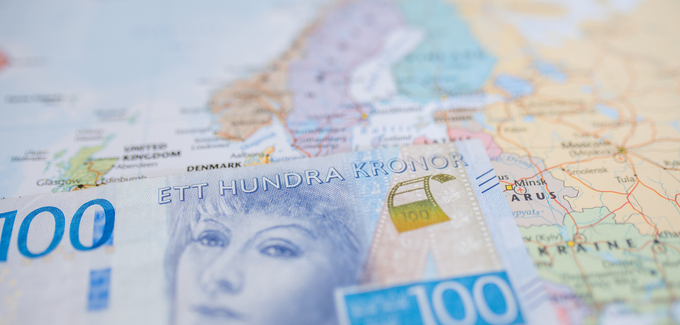 En hundrakronorssedel ligger på en karta över Europa