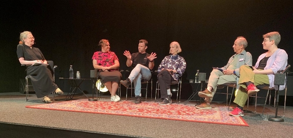 Fem paneldeltagare sitter på stolar på scenen tillsammans med samtalsmoderatorn