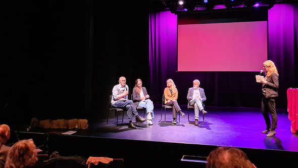 Panelmedlemmar diskuterar på en scen inför publik.