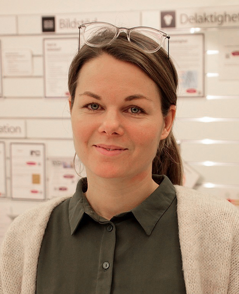 Fanny Iselidh med glasögon på huvudet ler mot kameran i en butik.