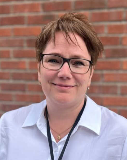 "Karoline Ericsson i ljus skjorta framför en tegelvägg"