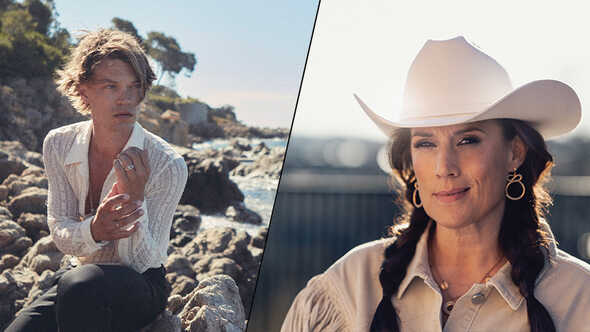 Kvinna i vit cowboyhatt och kvinna sittande på klippor vid havet.