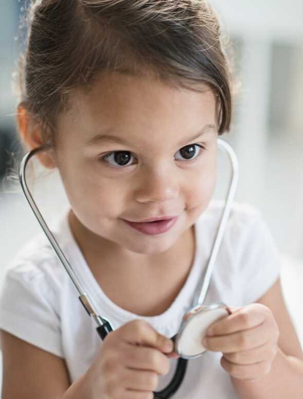 Litet barn leker med ett stetoskop.