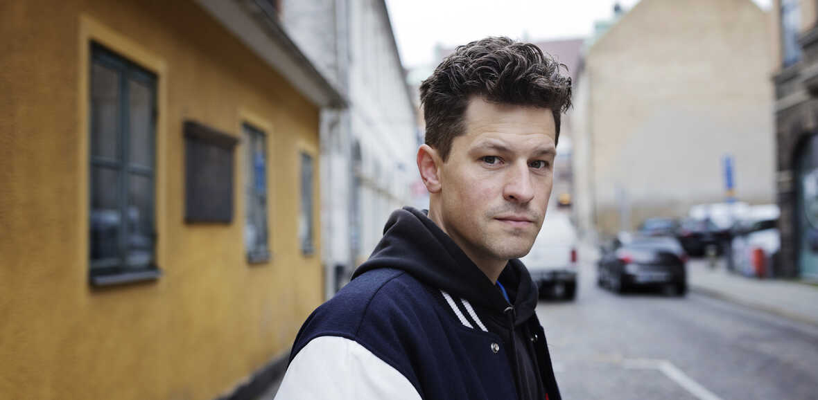 Föreläsaren Henrik Wahlström står på en gata med historiska byggnader i bakgrunden.