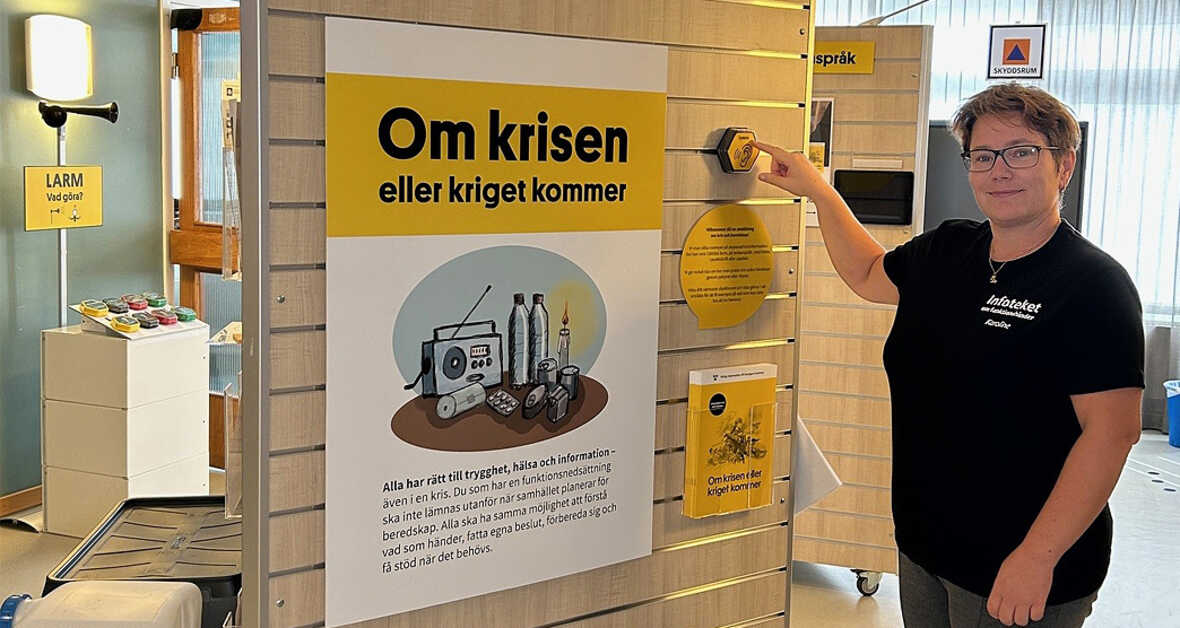 Kvinna visar informationsmaterial om beredskap vid kriser eller krig på bibliotek.