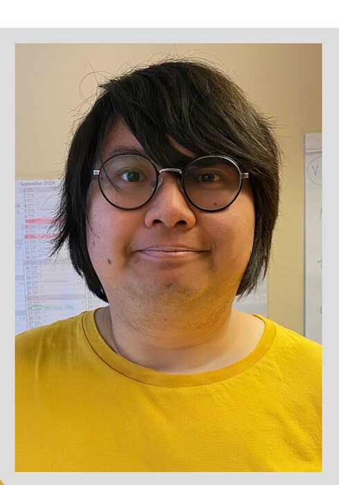 Porträtt av en leende man i gul tröja och runda glasögon.