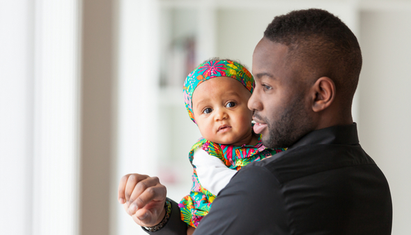 En pappa med ett litet barn i famnen.